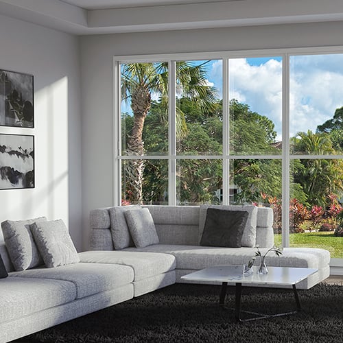 Bright room with modern grey and dark grey furniture, looking out onto a landscaped yard.