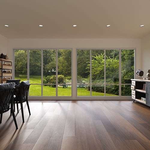 Bright room with modern grey and dark grey furniture, looking out onto a landscaped yard.