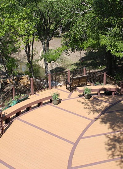 Birds eye view of a deck with benches and potted plants overlooking a creek.