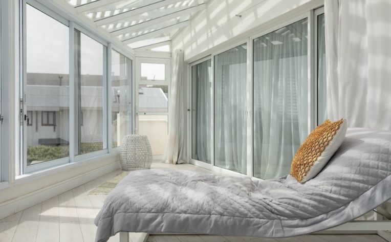 Sunroom with floor-to-ceiling windows, a cushioned lounge chair, and natural light overlooking neighboring homes.