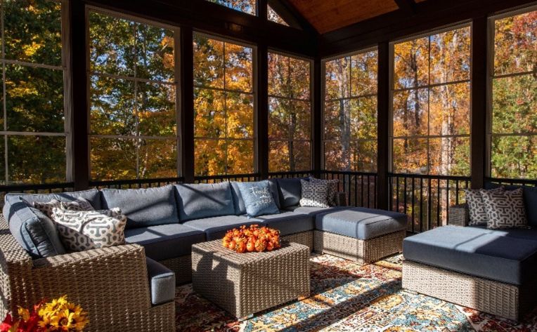 A sunroom in fall with a blue-cushioned grey sofa set and a centertable.